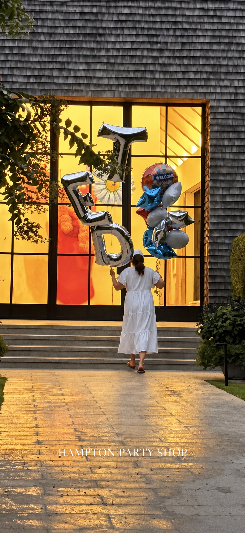 Hampton Party Shop delivery arriving with silver letter balloons and a blue and silver bouquet at a Hamptons home in the evening