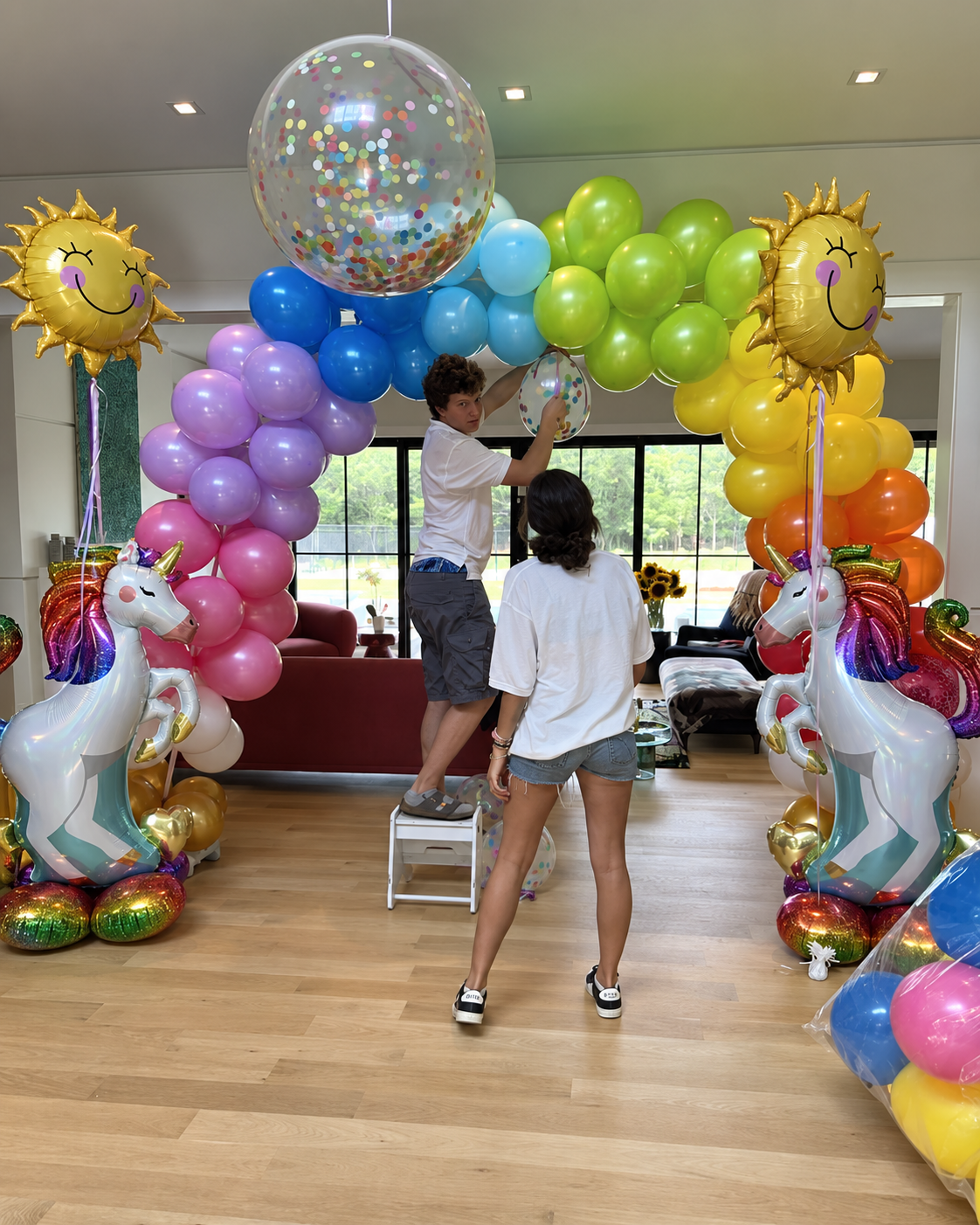 Rainbow balloon arch with unicorn and sun balloons being installed inside a Hamptons home